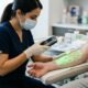 Healthcare provider using a handheld vein scanner projecting green light to visualize veins on a patient's forearm
